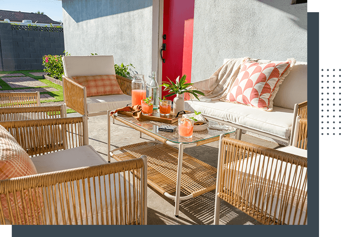 A patio with chairs, tables and pillows.