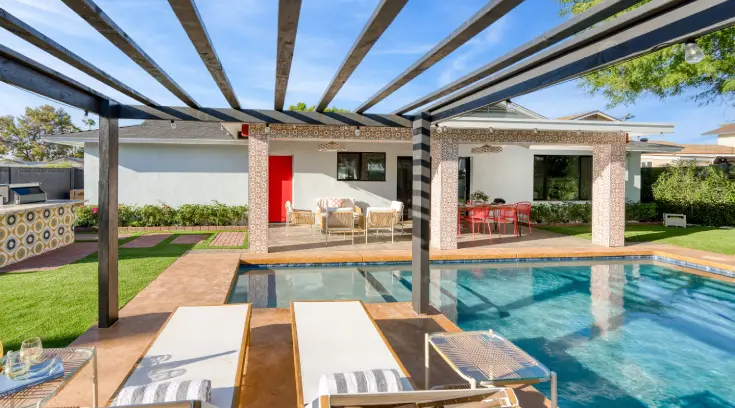 A pool with a red door and white chairs