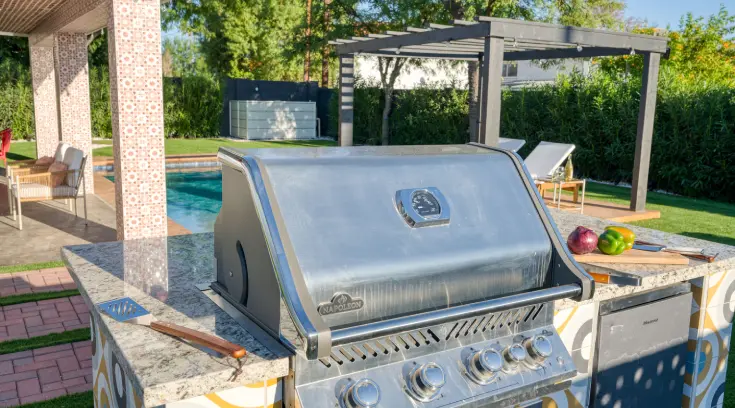 A grill that is sitting next to the pool.