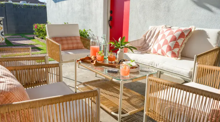 A patio with furniture and drinks on the table.