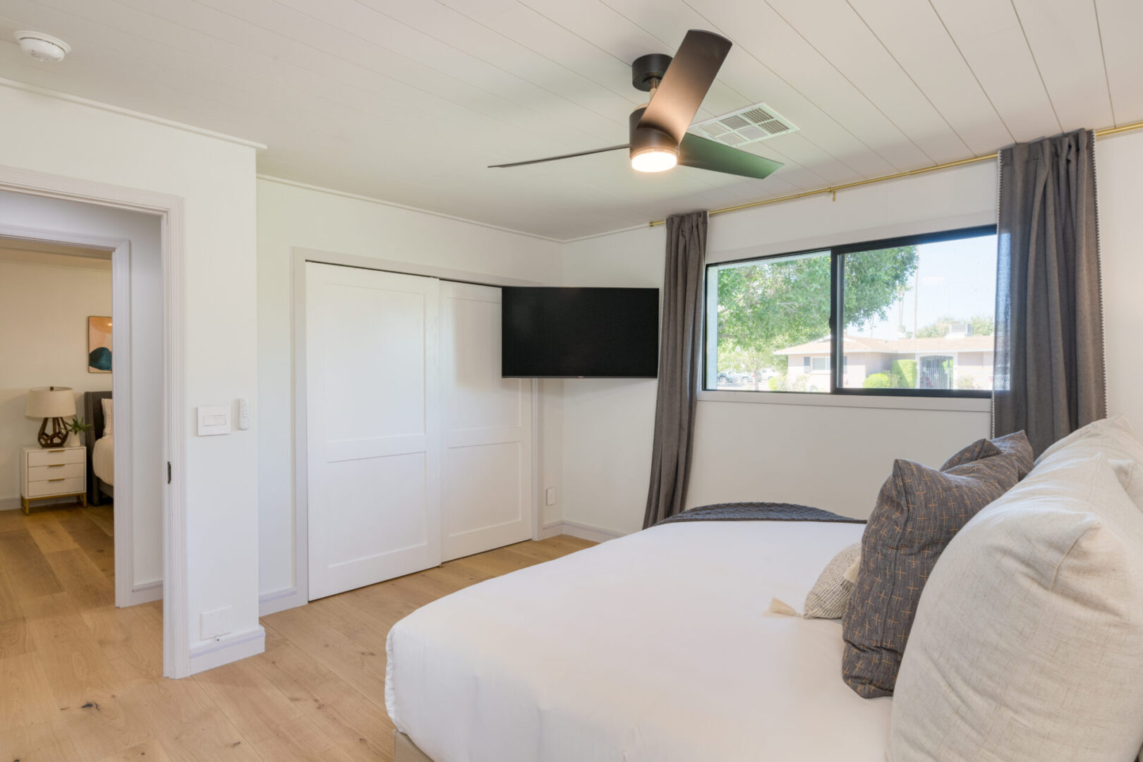 A bedroom with a bed, tv and window.