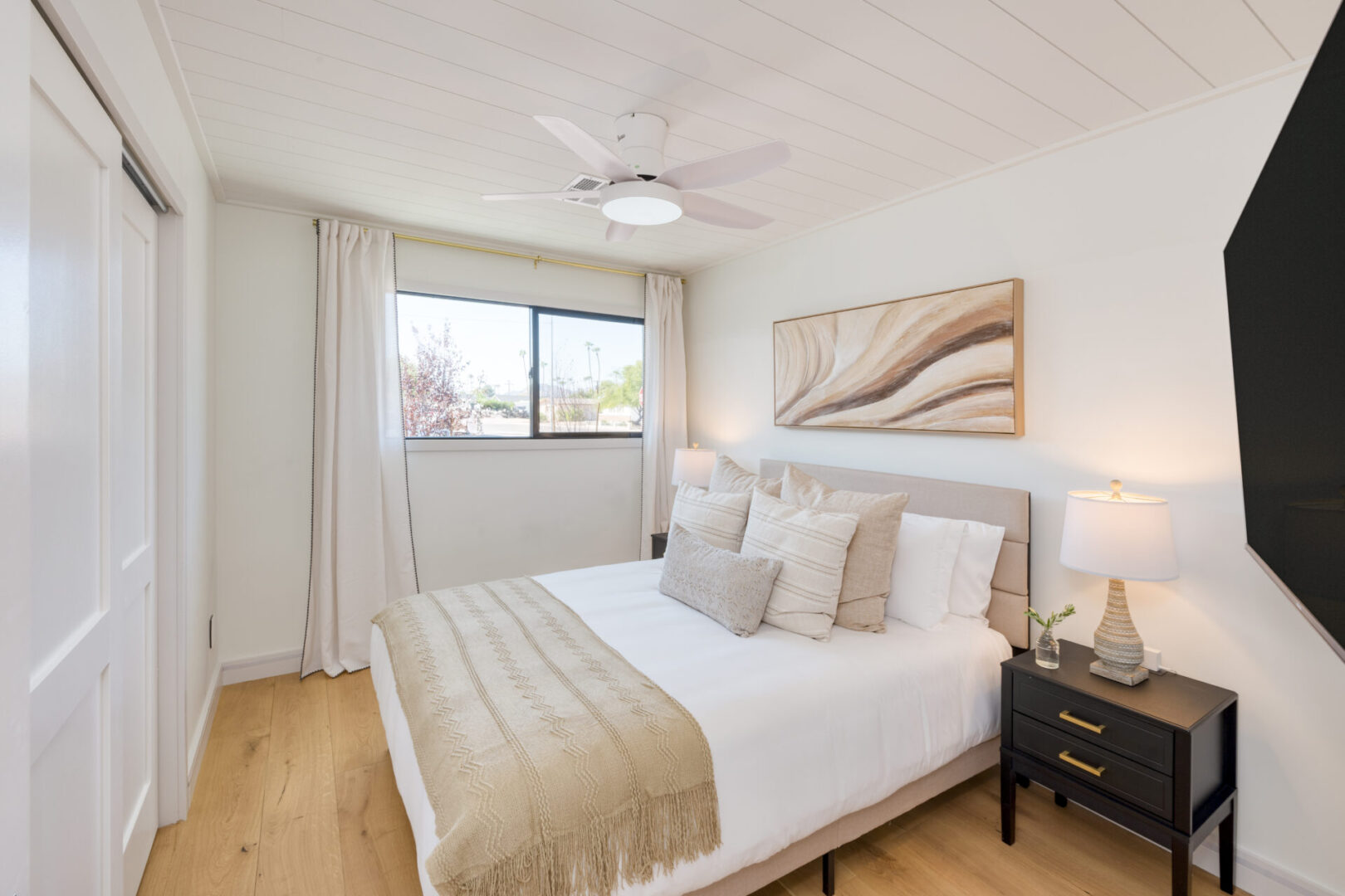 A bedroom with a bed, nightstand and window.