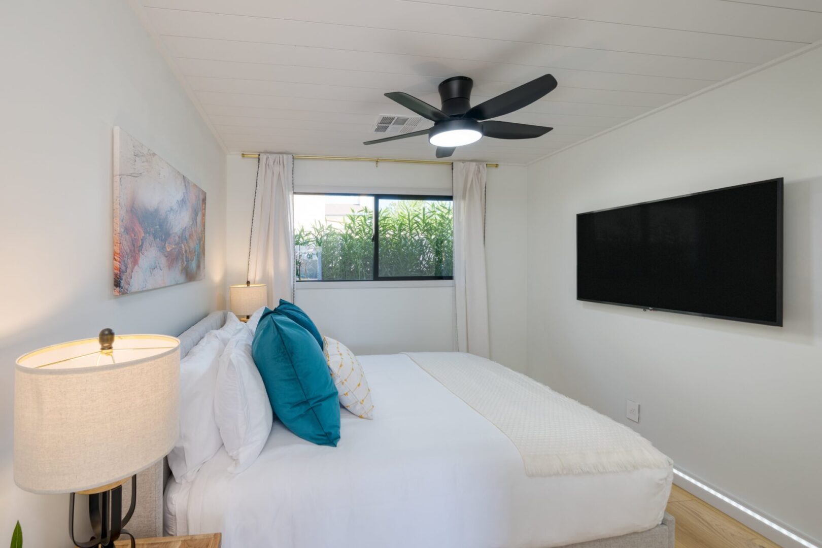 A bedroom with a bed, tv and window.