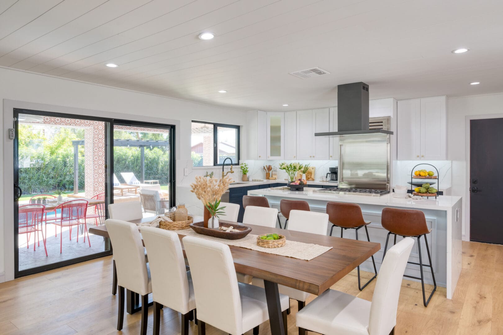 A dining room table with white chairs and a kitchen in the background.