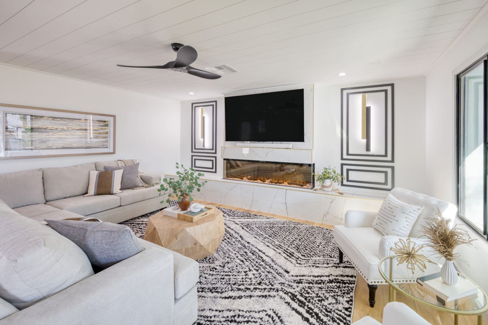 A living room with white furniture and a large screen tv.