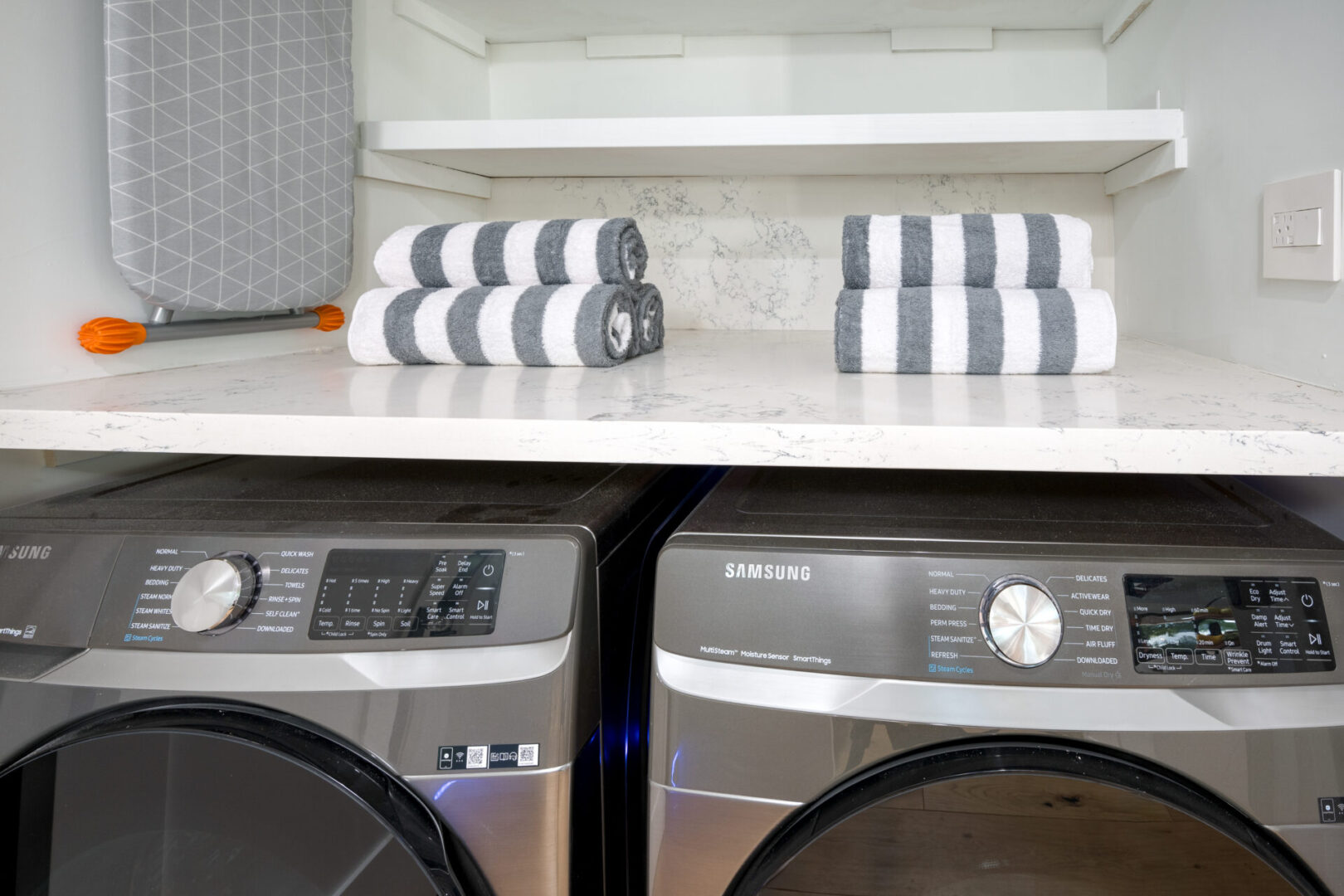 A white counter top with two gray and white towels.