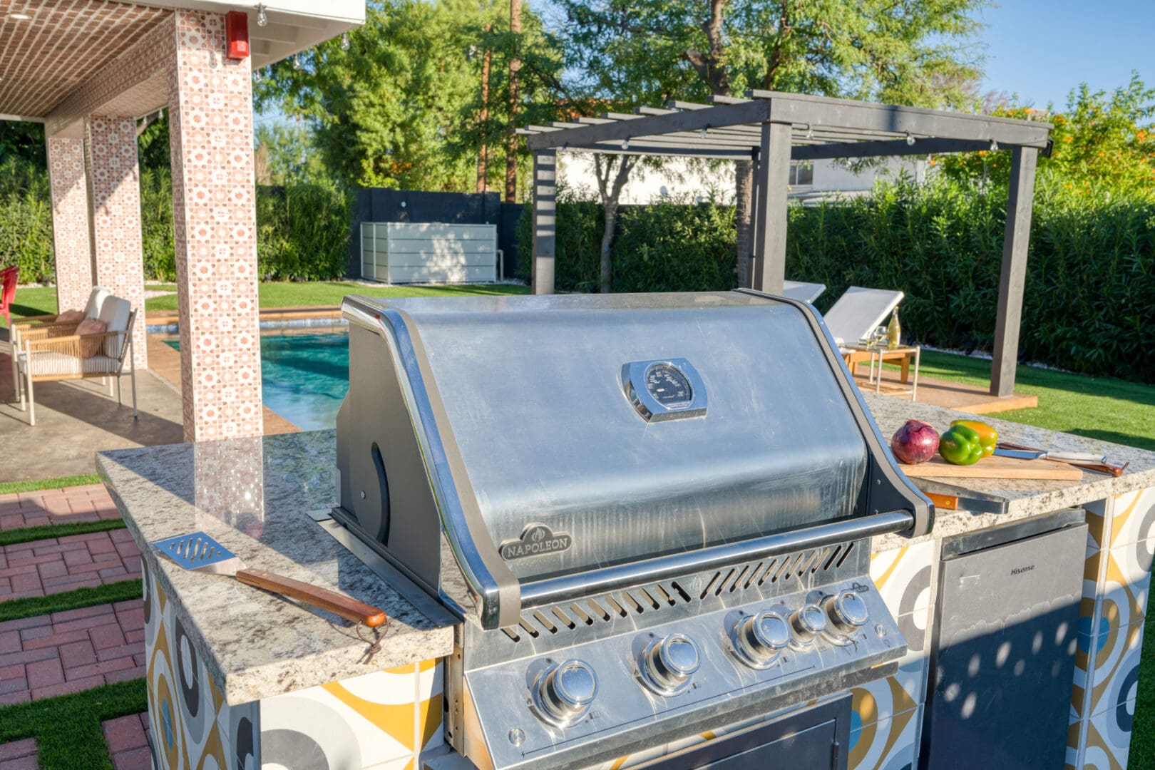 A grill that is sitting outside near the pool.