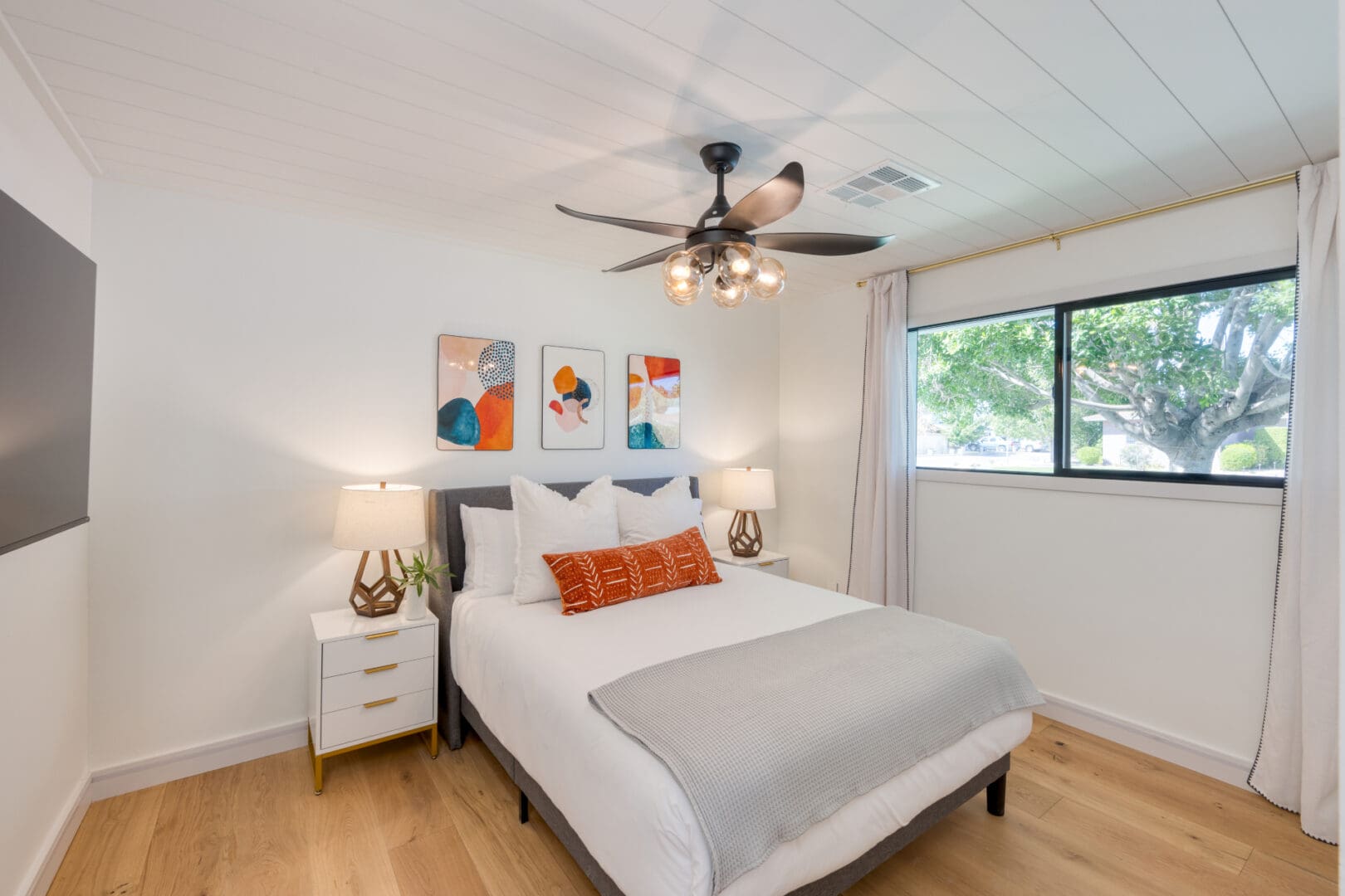 A bedroom with a bed, nightstand and ceiling fan.