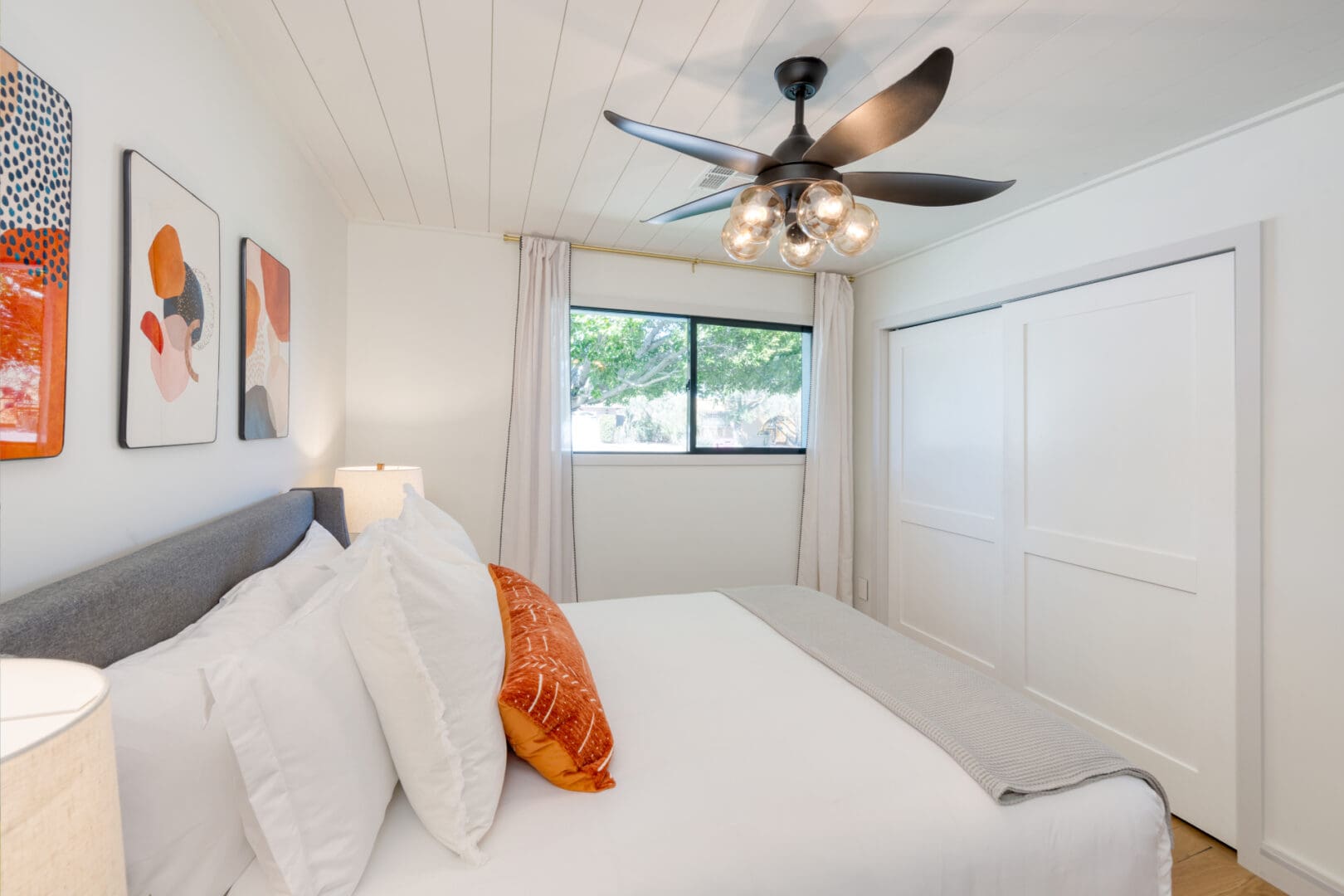 A bedroom with white walls and ceiling fan.