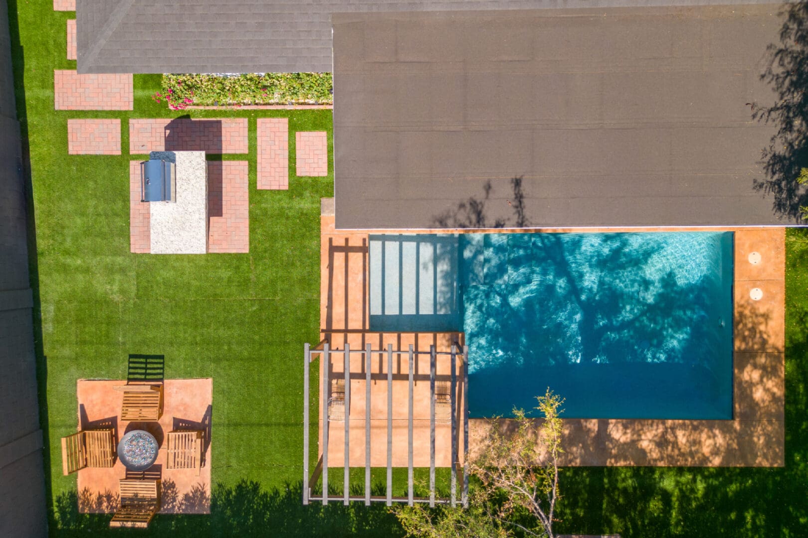 A backyard with pool, deck and grass.