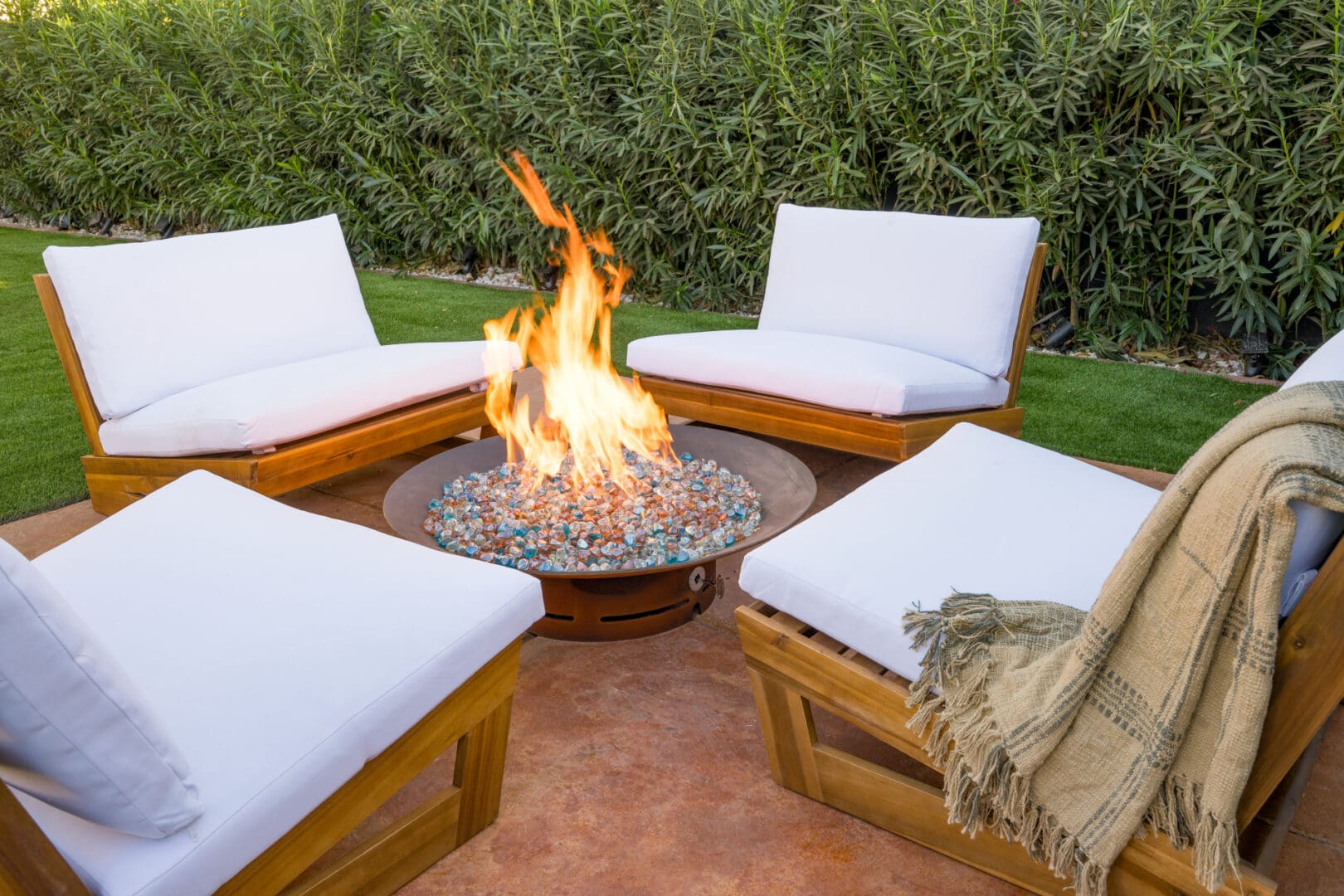 A fire pit with white cushions and pillows.