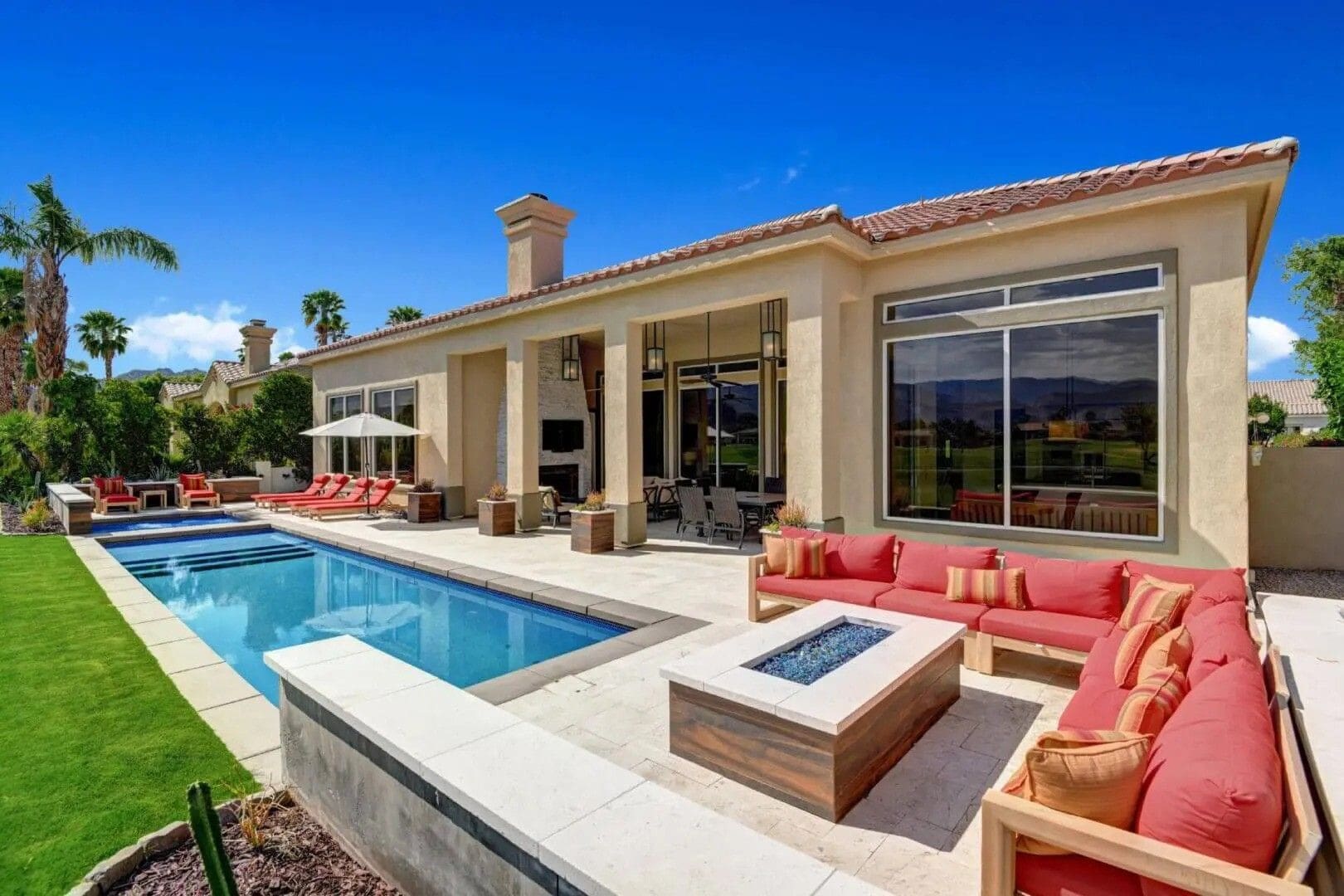 A large pool with a fire pit and lounge chairs.