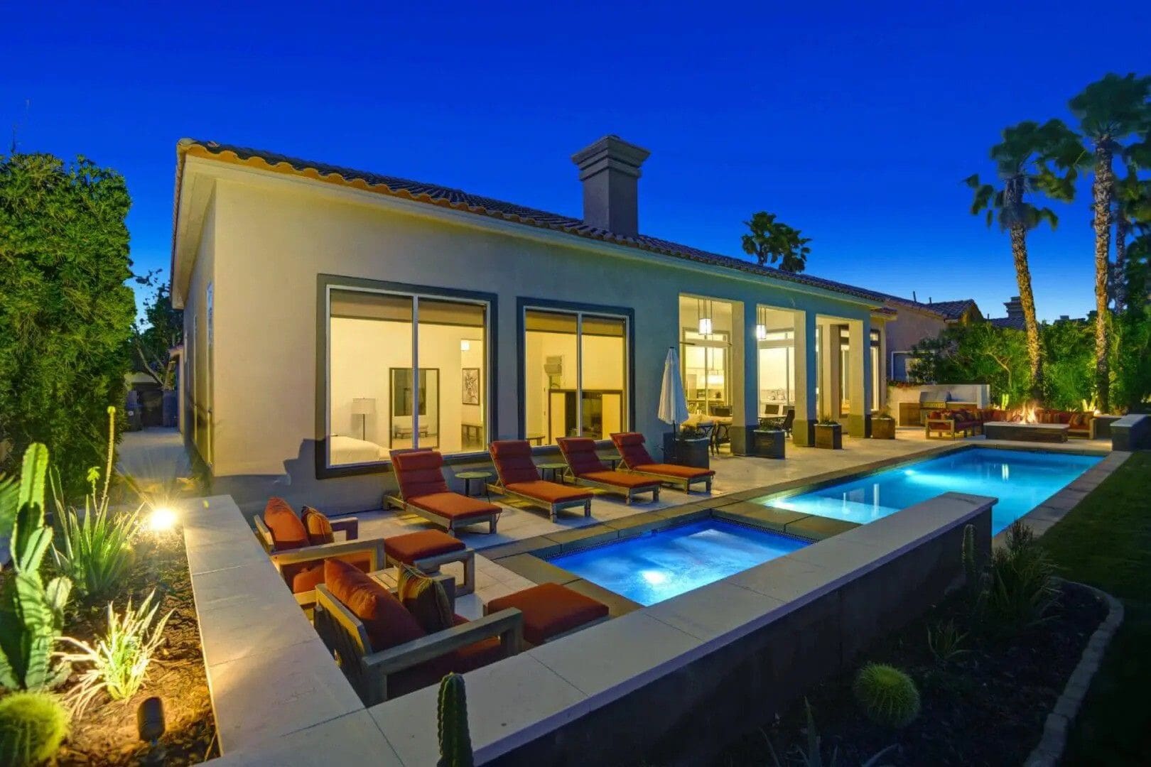 A pool with lounge chairs and a fire pit.